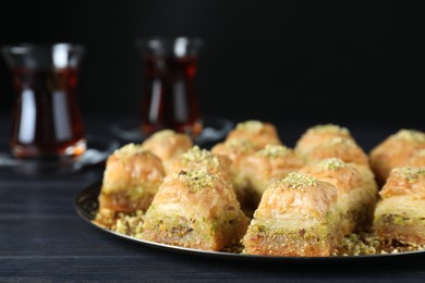Photo of Delicious fresh baklava with chopped nuts on black wooden table, closeup. Eastern sweets