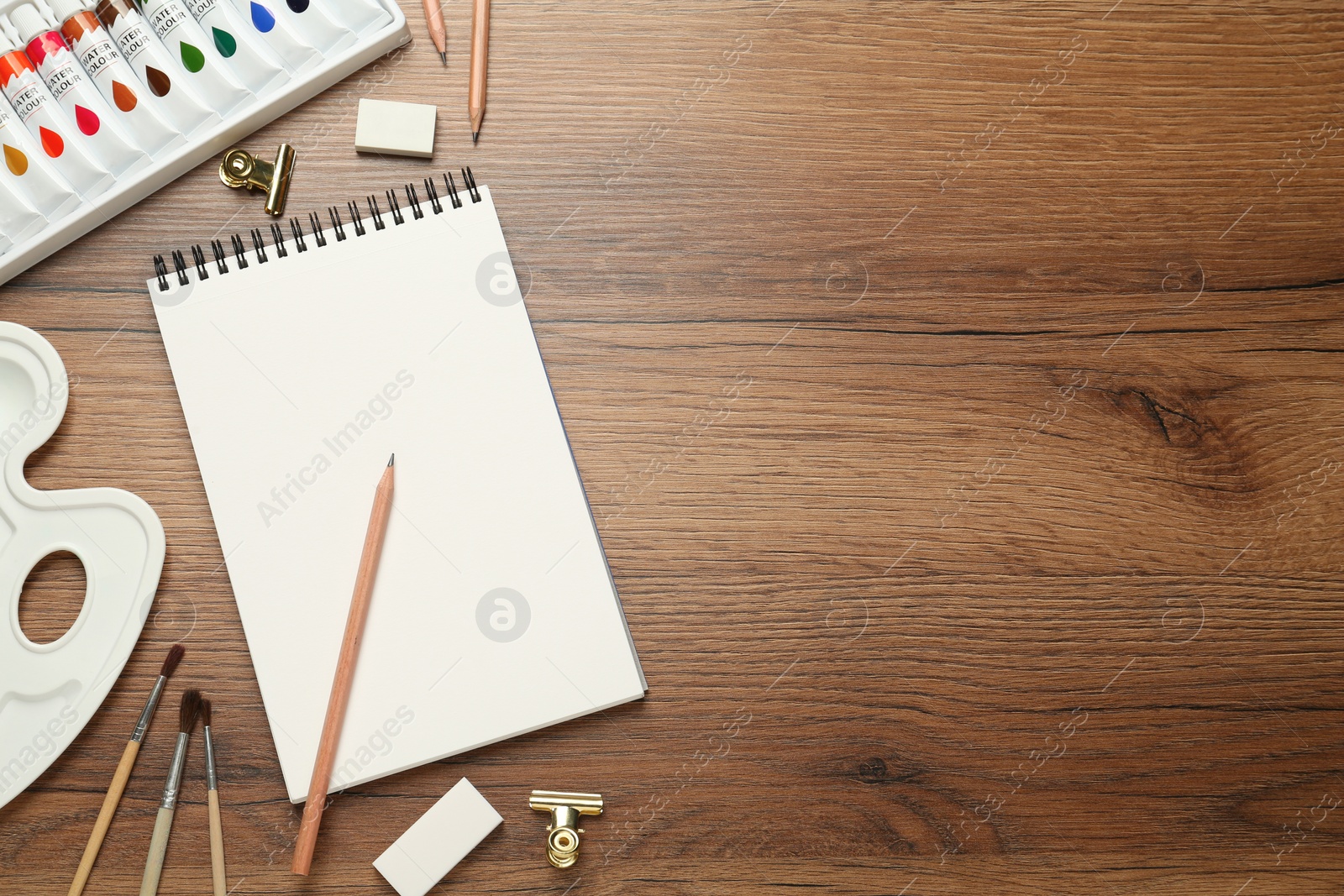 Photo of Flat lay composition with sketchbook and drawing tools on wooden table, space for text