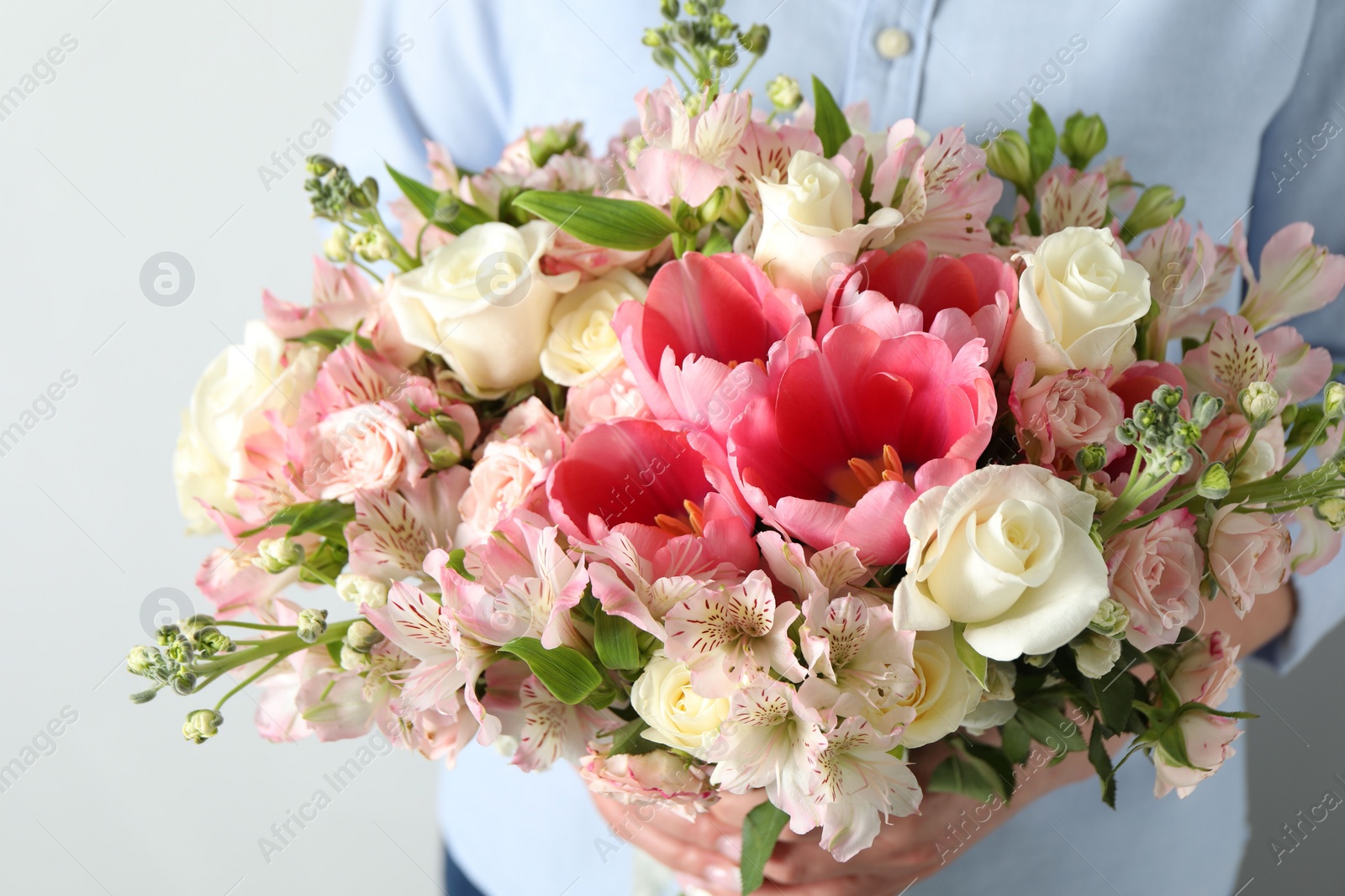 Photo of Woman with beautiful bouquet of fresh flowers on light background, closeup