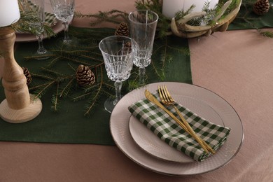 Photo of Christmas place setting with cutlery, glasses and festive decor on table