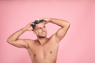 Photo of Handsome man washing hair on pink background