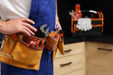 Photo of Professional plumber with tool belt indoors, closeup. Space for text