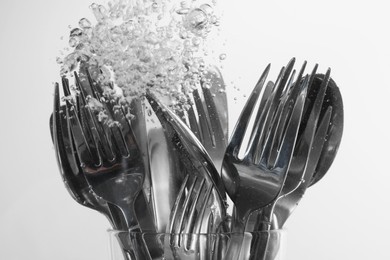 Photo of Washing silver cutlery in water on white background