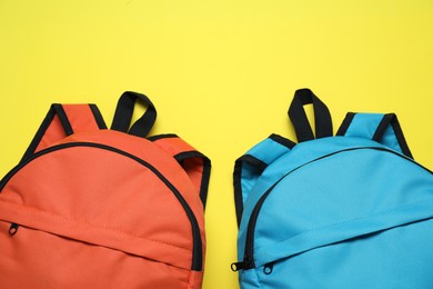 Stylish backpacks on yellow background, flat lay