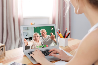 Image of Young woman having video chat with her grandparents at home, focus on screen