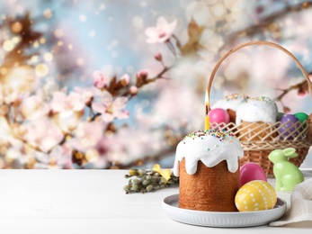 Image of Easter cake and painted eggs on white table outdoors, space for text
