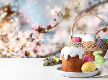 Easter cake and painted eggs on white table outdoors, space for text