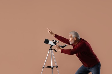 Senior astronomer with telescope on brown background. Space for text