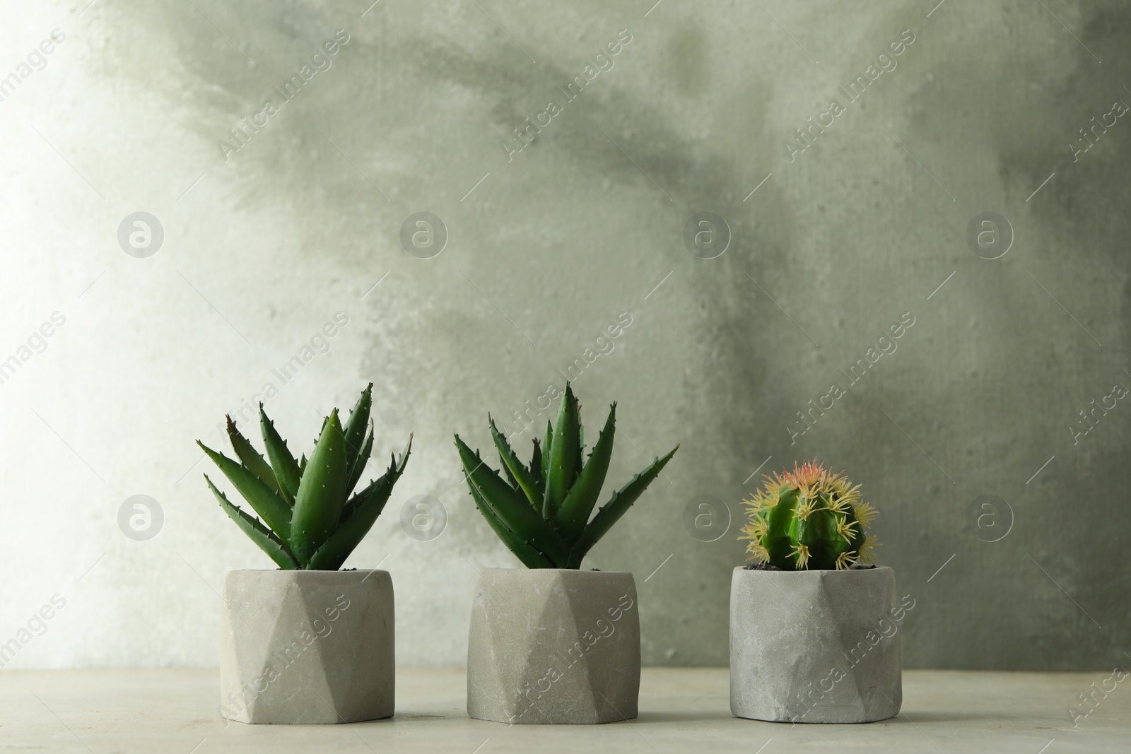 Photo of Artificial plants in flower pots on light grey stone table