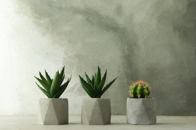 Artificial plants in flower pots on light grey stone table