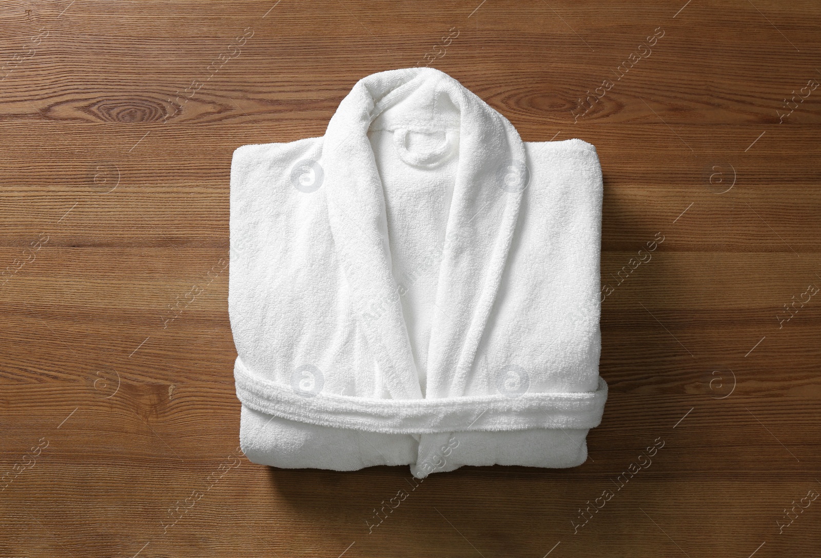 Photo of Clean folded bathrobe on wooden background, top view