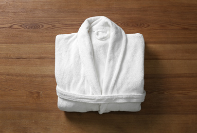 Photo of Clean folded bathrobe on wooden background, top view