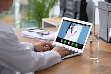 Image of Doctor having online video consultation with business trainer at table, closeup