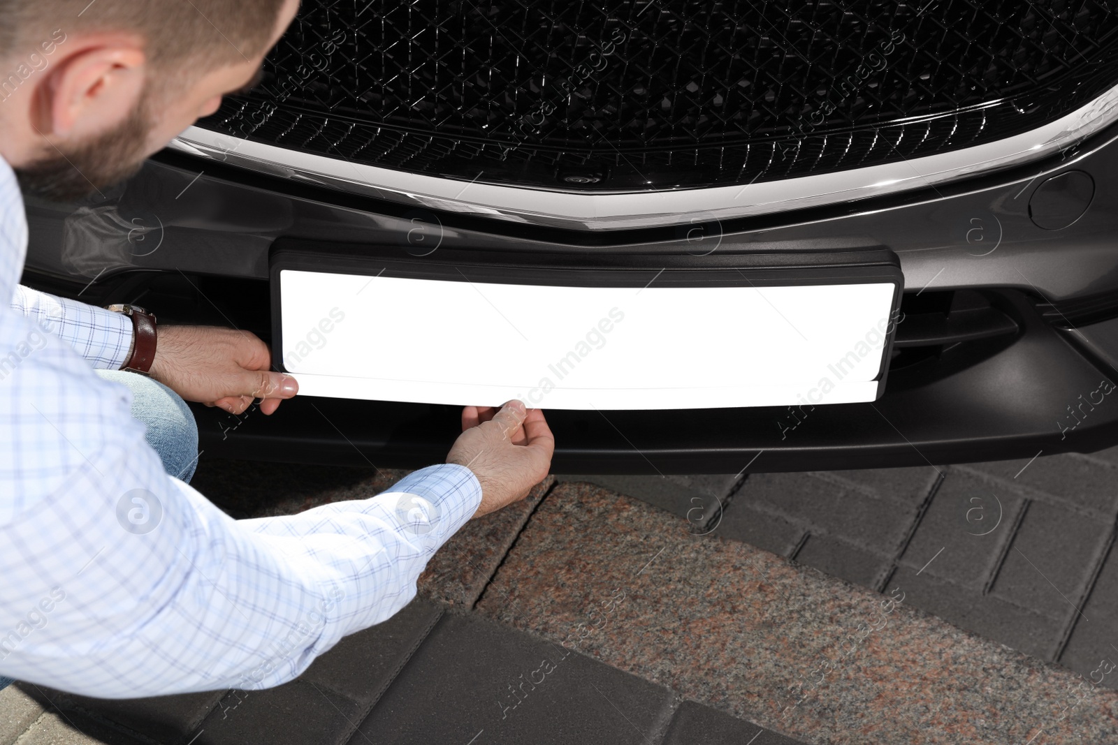 Photo of Man installing vehicle registration plate outdoors, closeup. Mockup for design