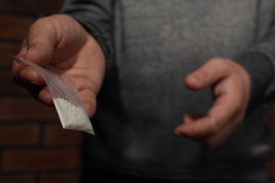 Photo of Drug addiction. Man with plastic bag of cocaine on blurred background, selective focus