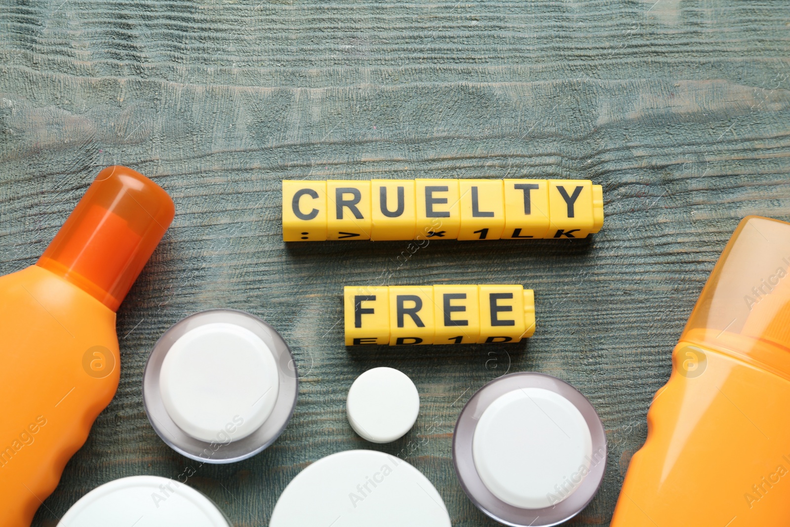 Photo of Flat lay composition with words Cruelty Free and different cosmetic products not tested on animals against light blue wooden background