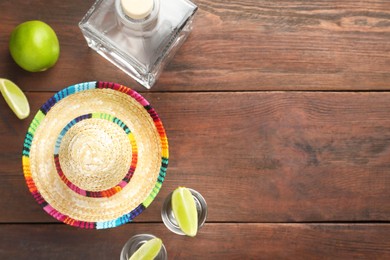 Mexican sombrero hat, tequila and lime on wooden table, flat lay. Space for text