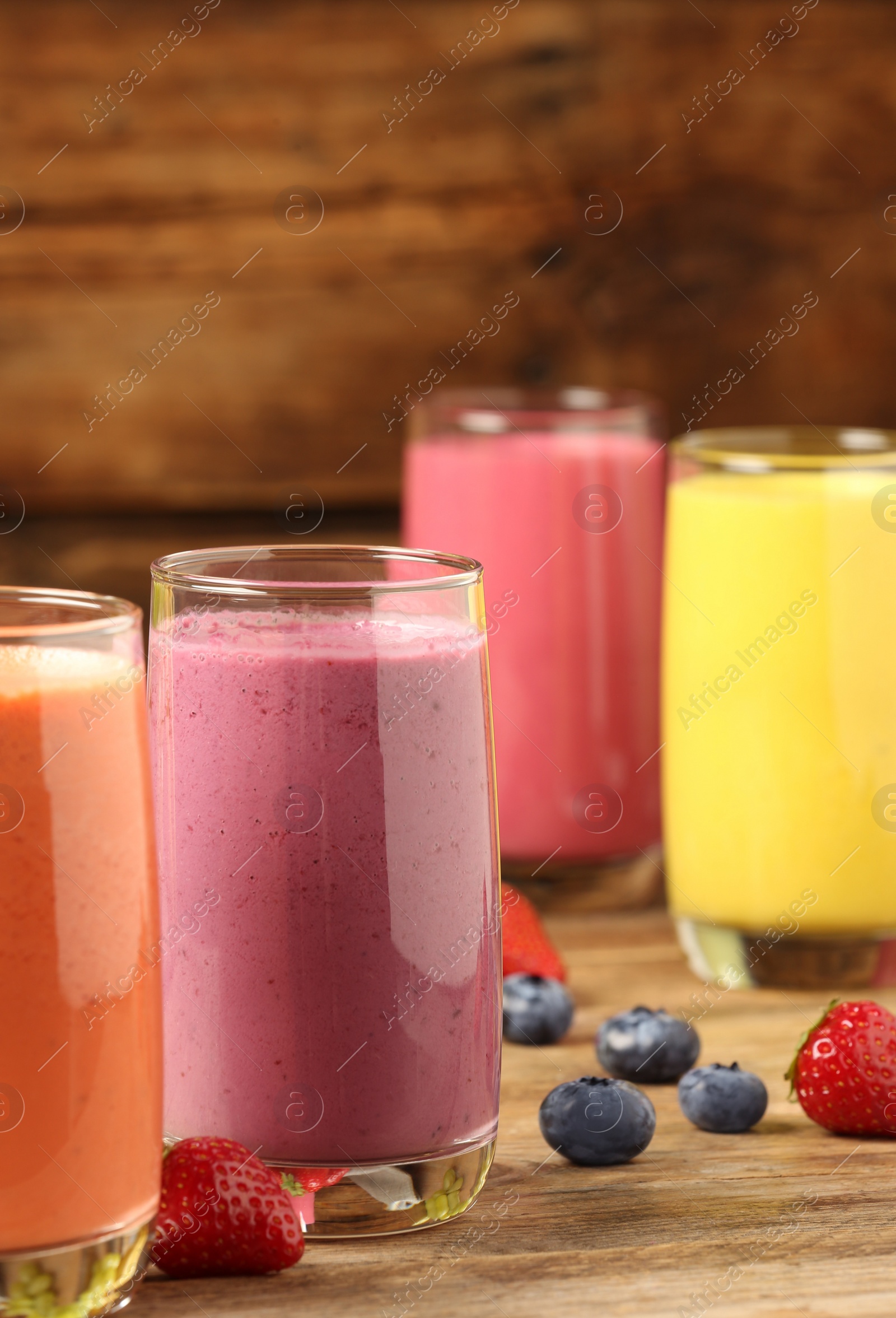 Photo of Glasses with different tasty smoothies on wooden table