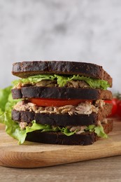 Delicious sandwich with tuna, tomatoes and lettuce on wooden table, closeup. Space for text