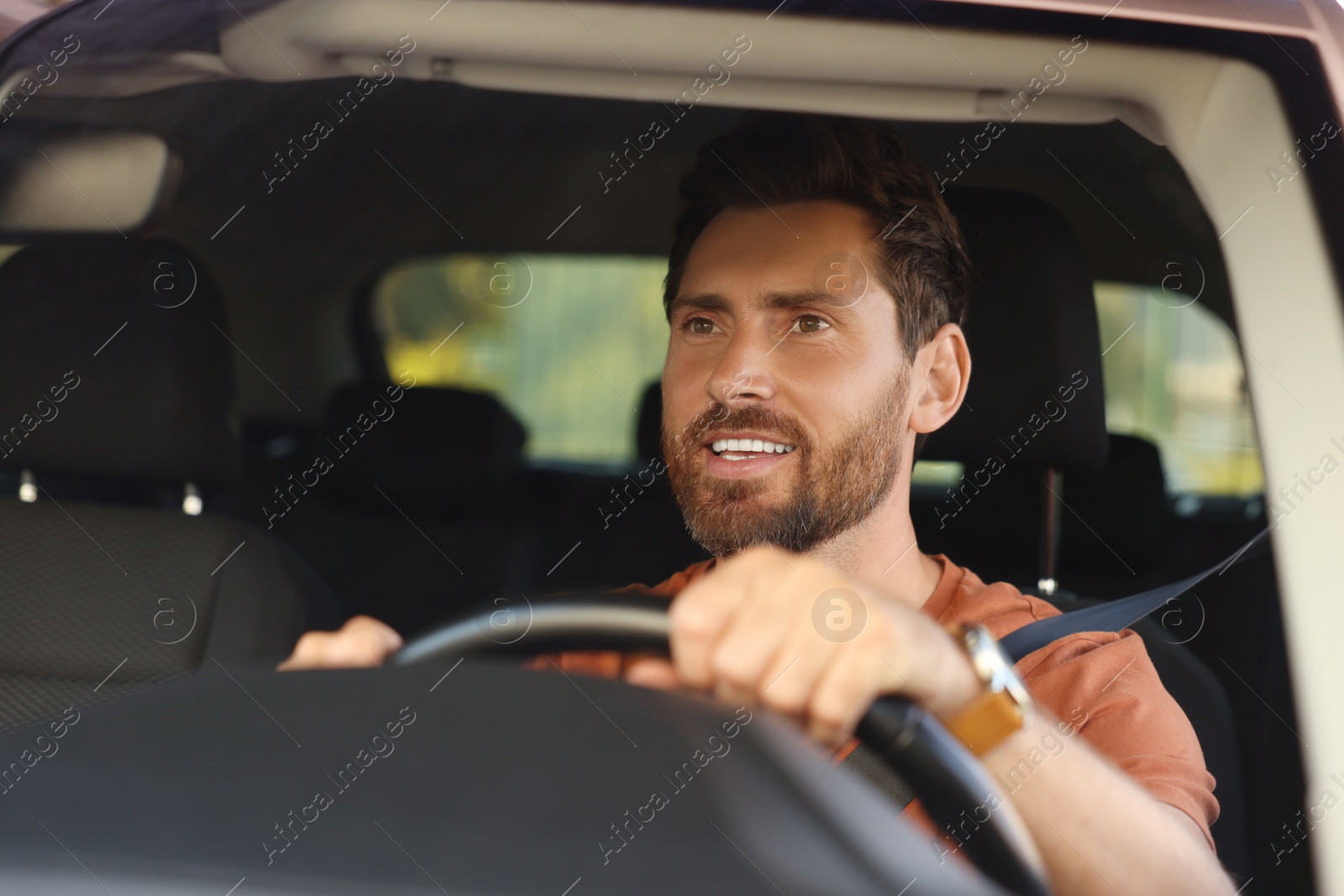 Photo of Enjoying trip. Happy bearded man driving car, view through windshield