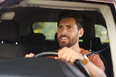 Photo of Enjoying trip. Happy bearded man driving car, view through windshield