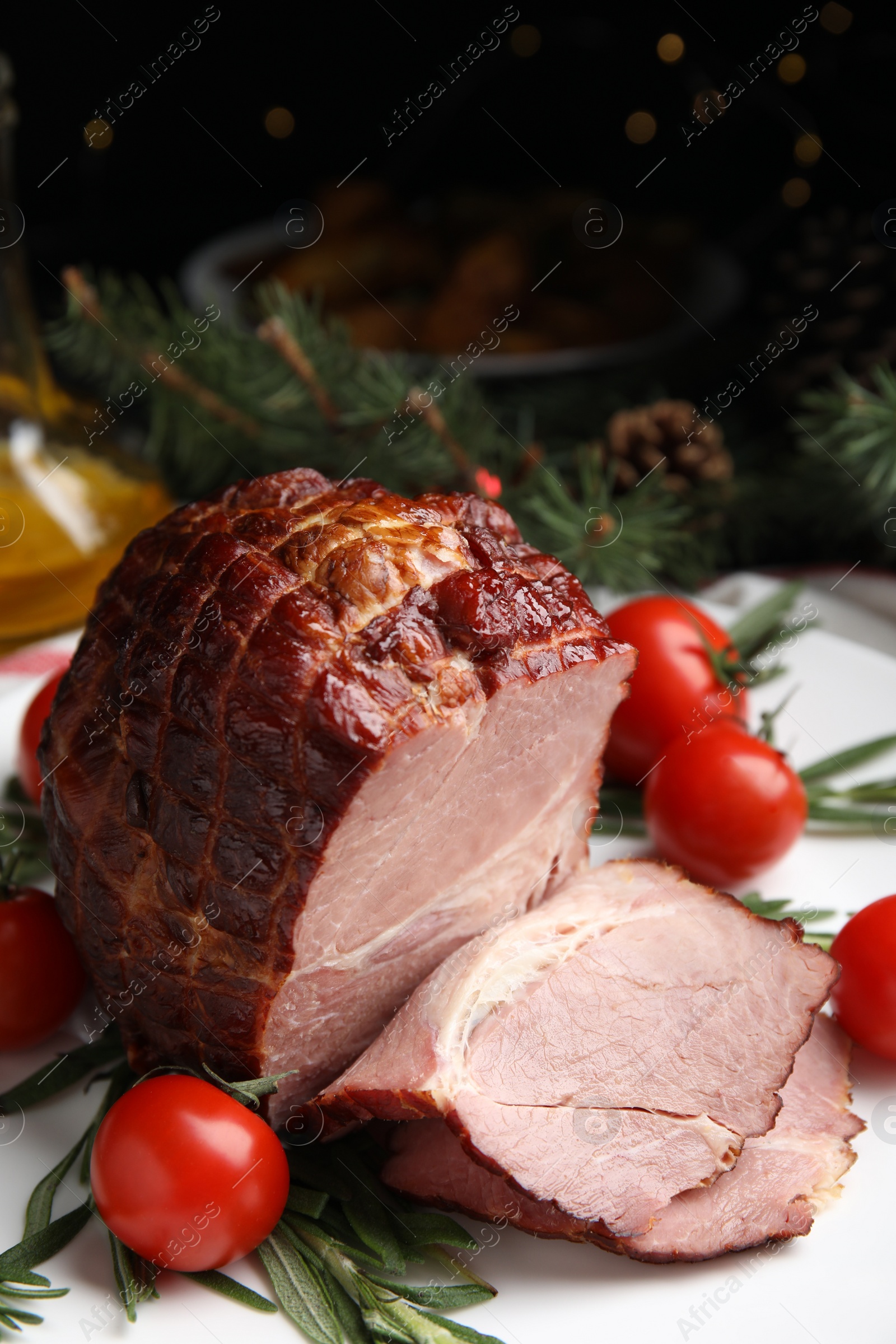Photo of Cut delicious ham with rosemary and tomatoes on white plate