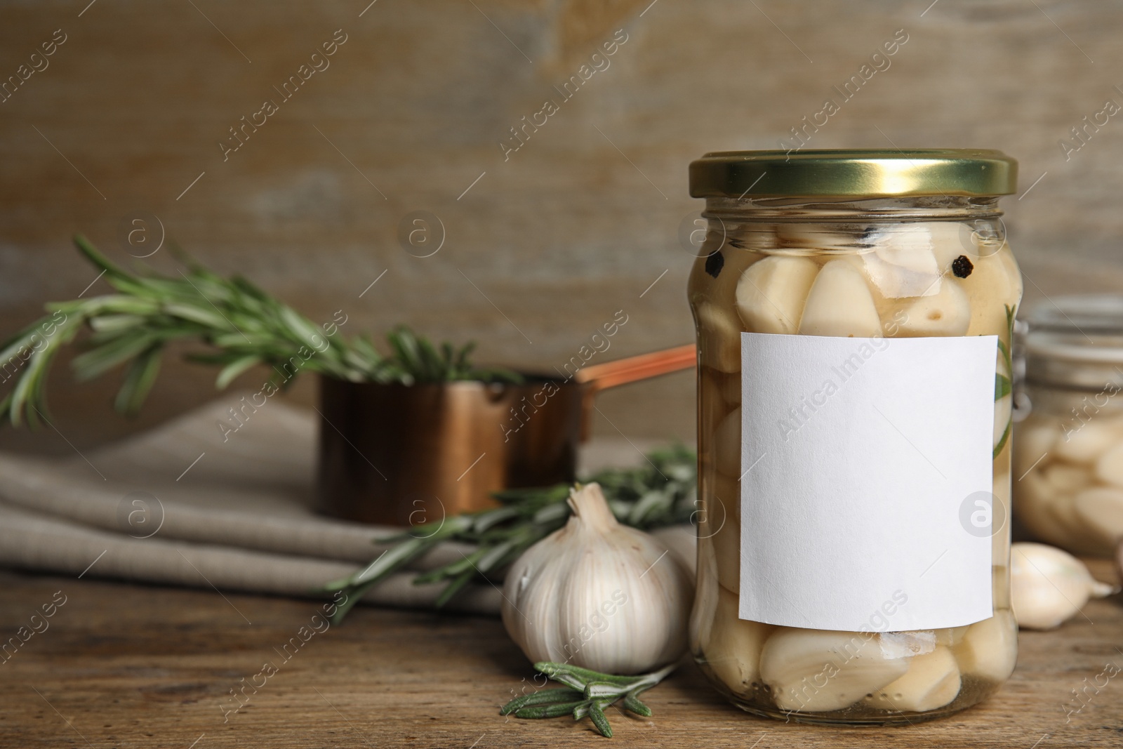 Photo of Composition with jar of pickled garlic on wooden table. Space for text