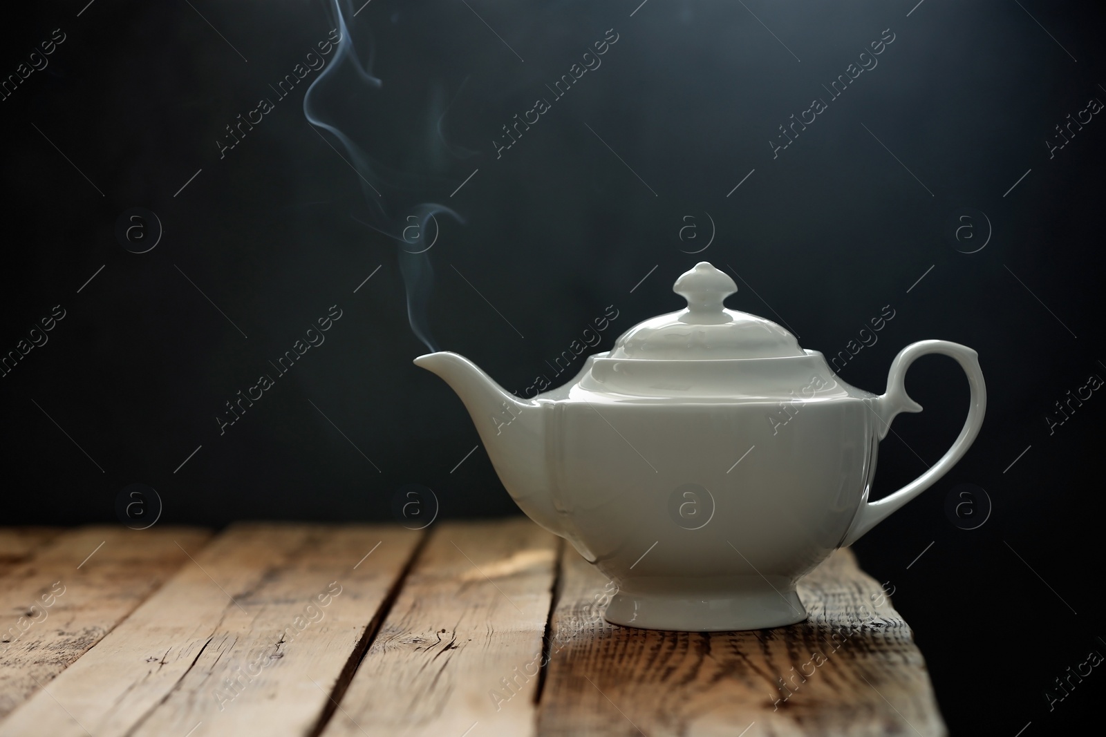 Photo of Porcelain tea pot on wooden table against gray background