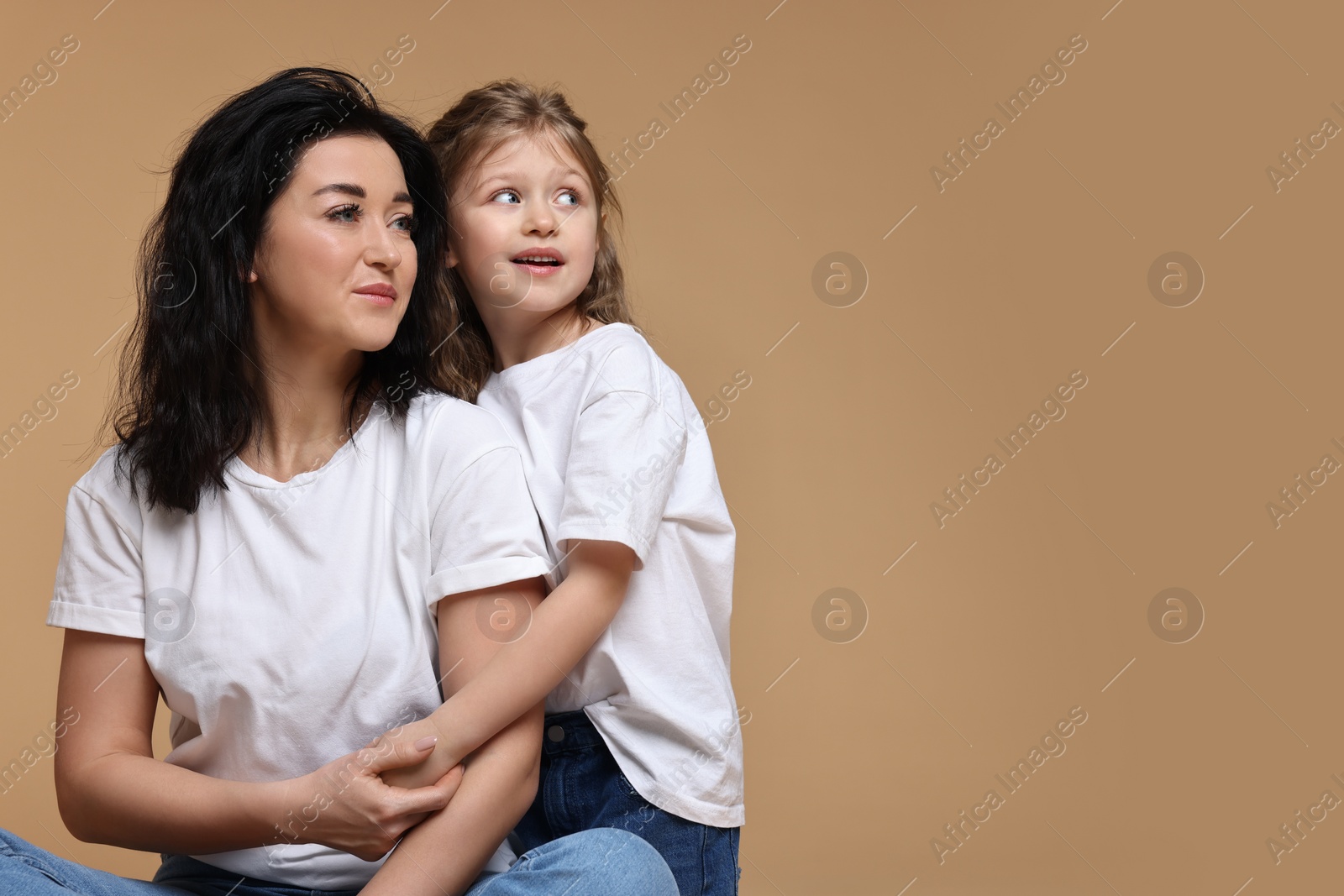 Photo of Beautiful mother with little daughter on beige background. Space for text