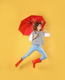 Woman with red umbrella near color wall