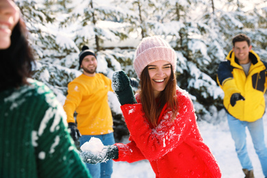 Photo of Happy friends playing snowballs outdoors. Winter vacation