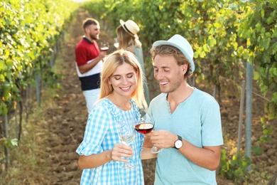 Young couple holding glasses of wine at vineyard