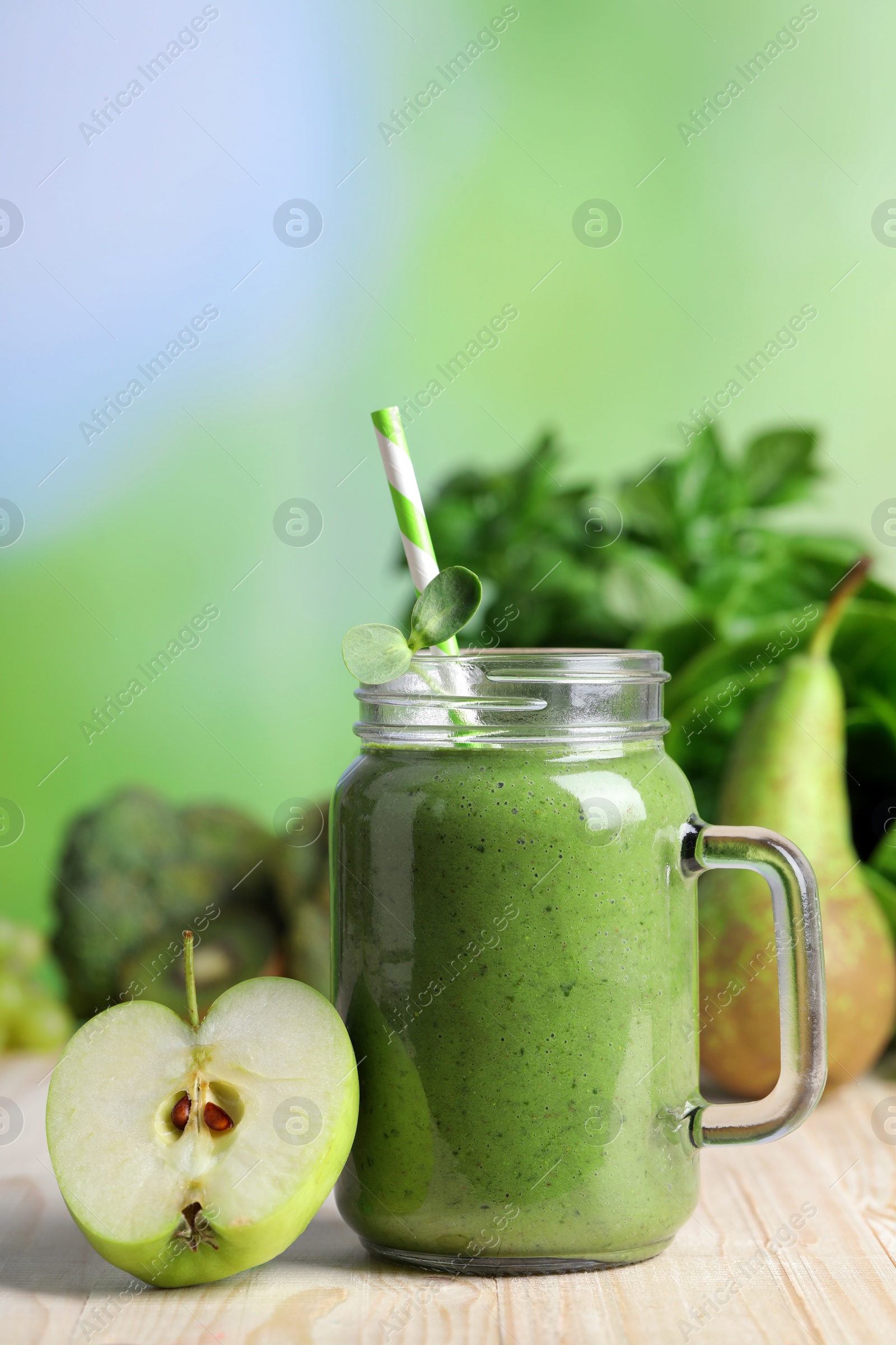 Photo of Mason jar of fresh green smoothie and ingredients on wooden table