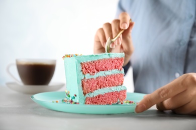 Woman eating fresh delicious birthday cake at table, closeup