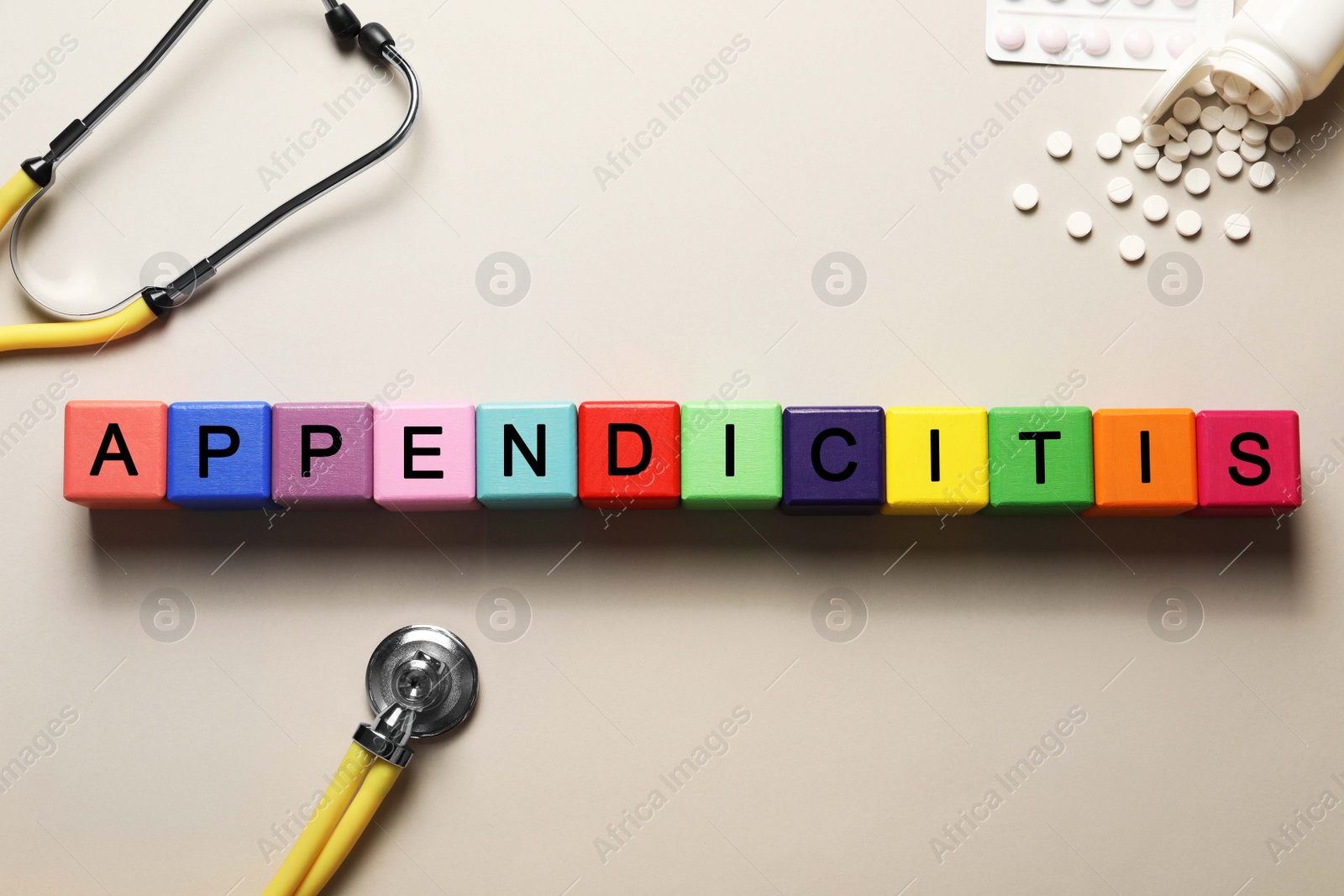 Photo of Word Appendicitis made of color cubes, pills and stethoscope on light background, flat lay