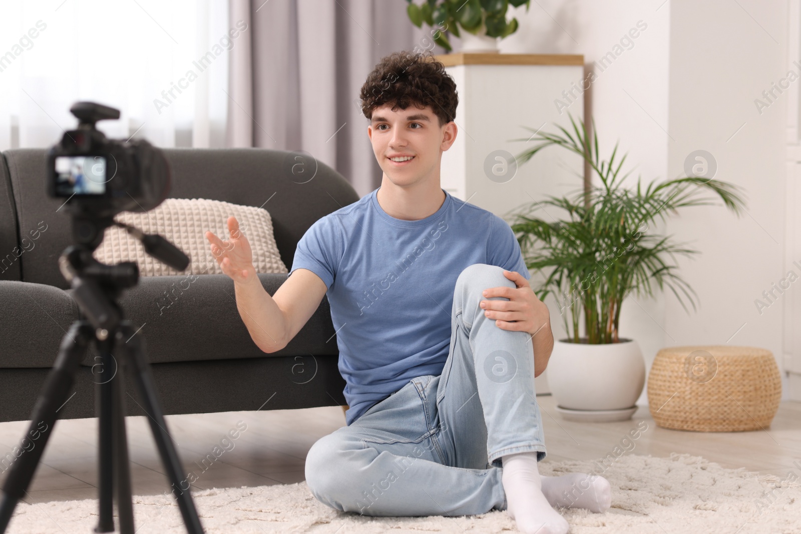 Photo of Smiling teenage blogger explaining something while streaming at home