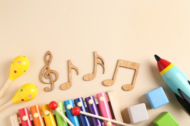 Baby song concept. Wooden notes, kids xylophone and toys on beige background, flat lay. Space for text