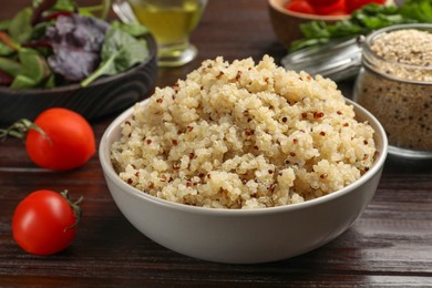 Photo of Tasty quinoa porridge in bowl on wooden table, closeup