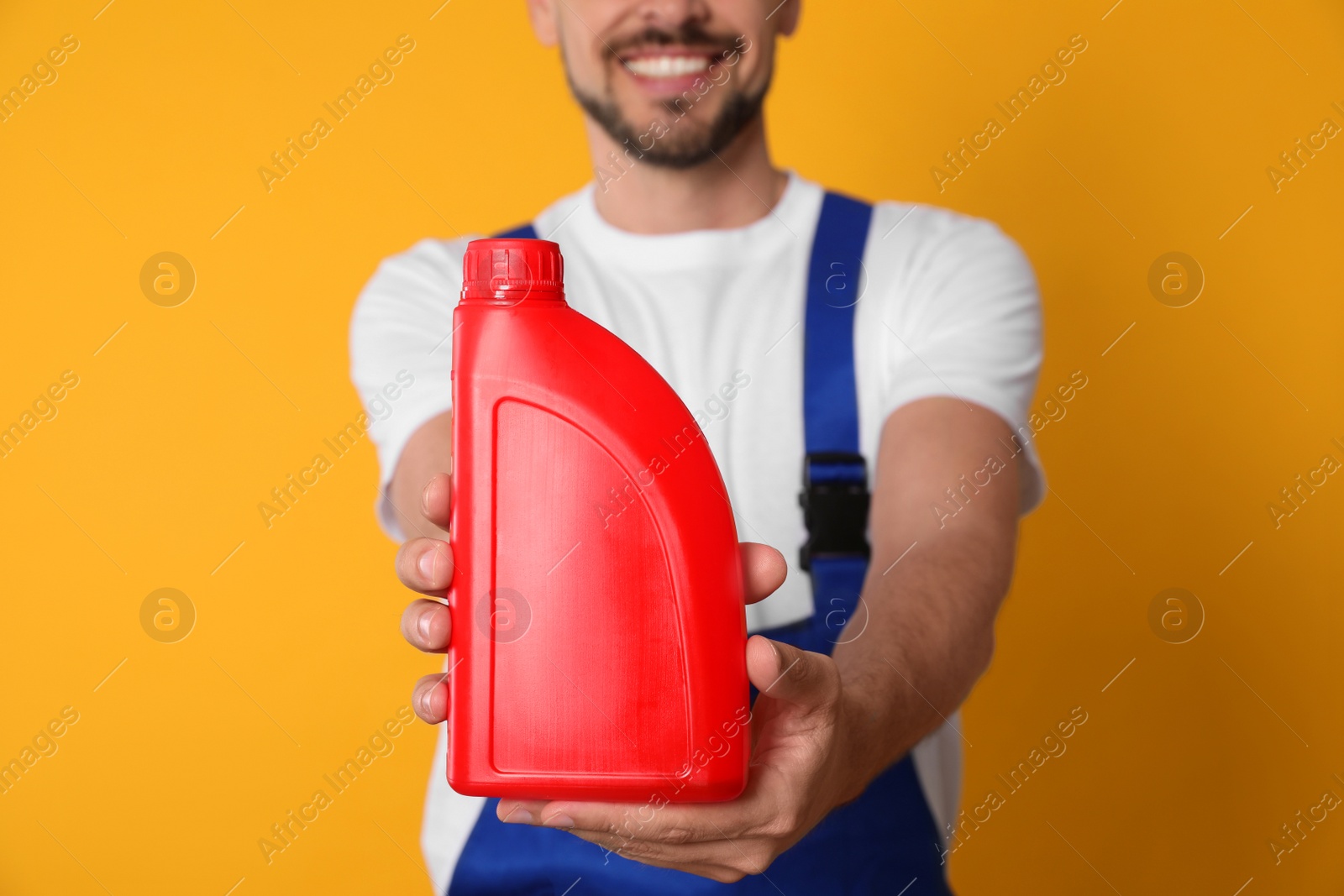 Photo of Man showing red container of motor oil on orange background, closeup
