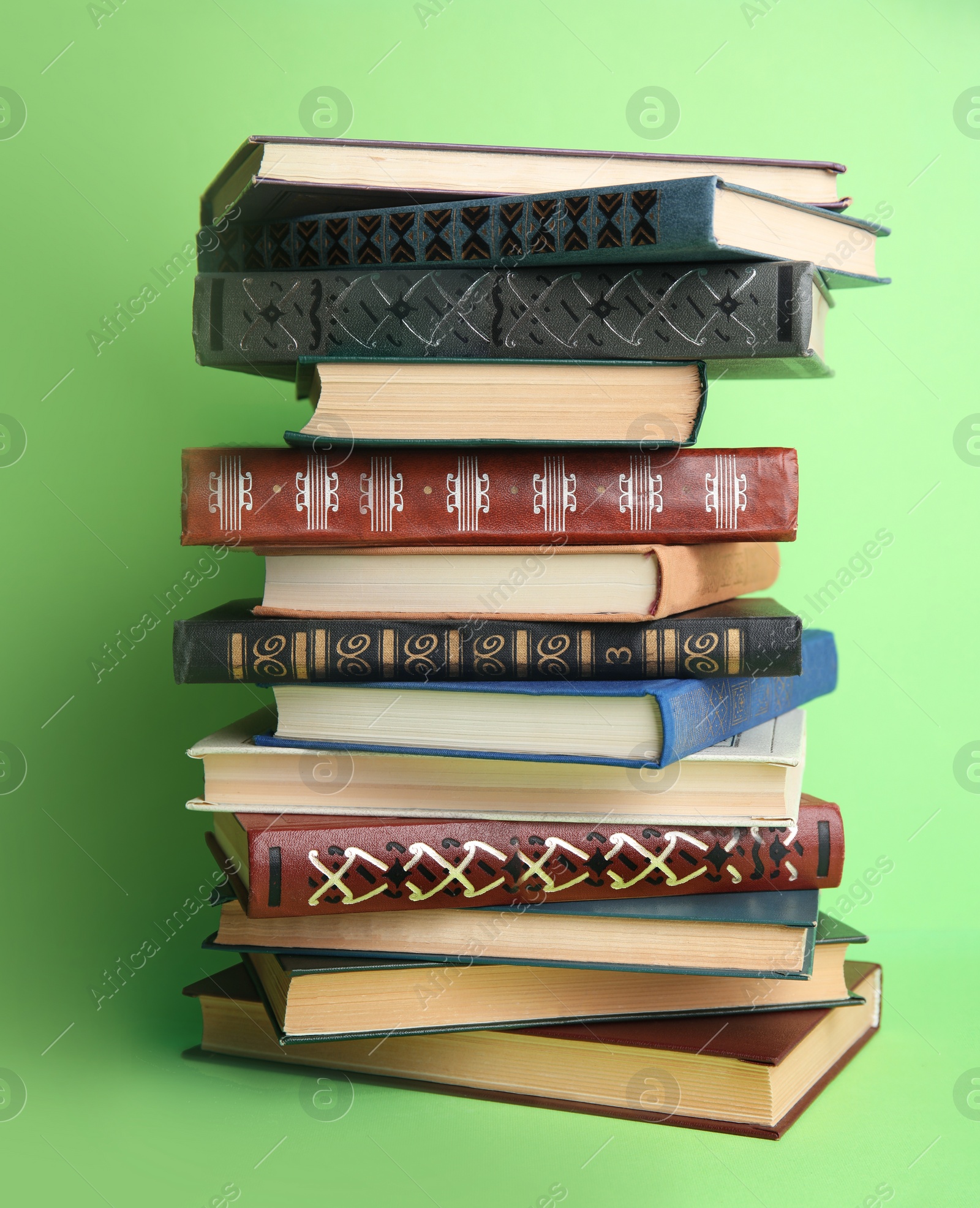 Photo of Stack of hardcover books on green background. Space for text