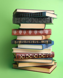 Stack of hardcover books on green background. Space for text