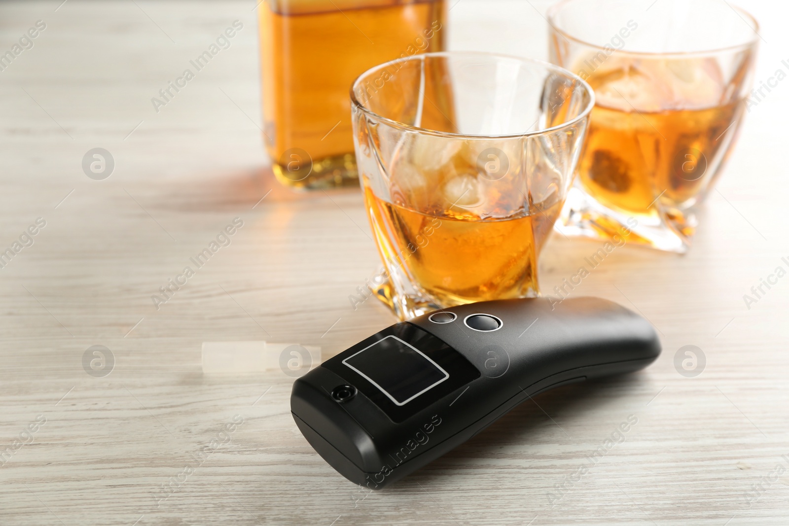 Photo of Modern breathalyzer and alcohol on white wooden table