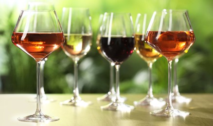 Different tasty wines in glasses on wooden table