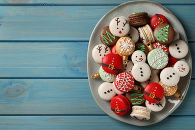 Photo of Beautifully decorated Christmas macarons on light blue wooden table, top view. Space for text