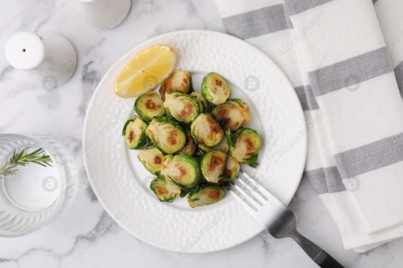 Photo of Delicious roasted Brussels sprouts served on white marble table, flat lay