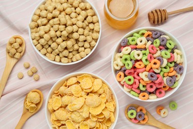 Photo of Different breakfast cereals and honey on napkin, flat lay