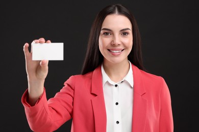 Photo of Happy woman holding blank business card on black background