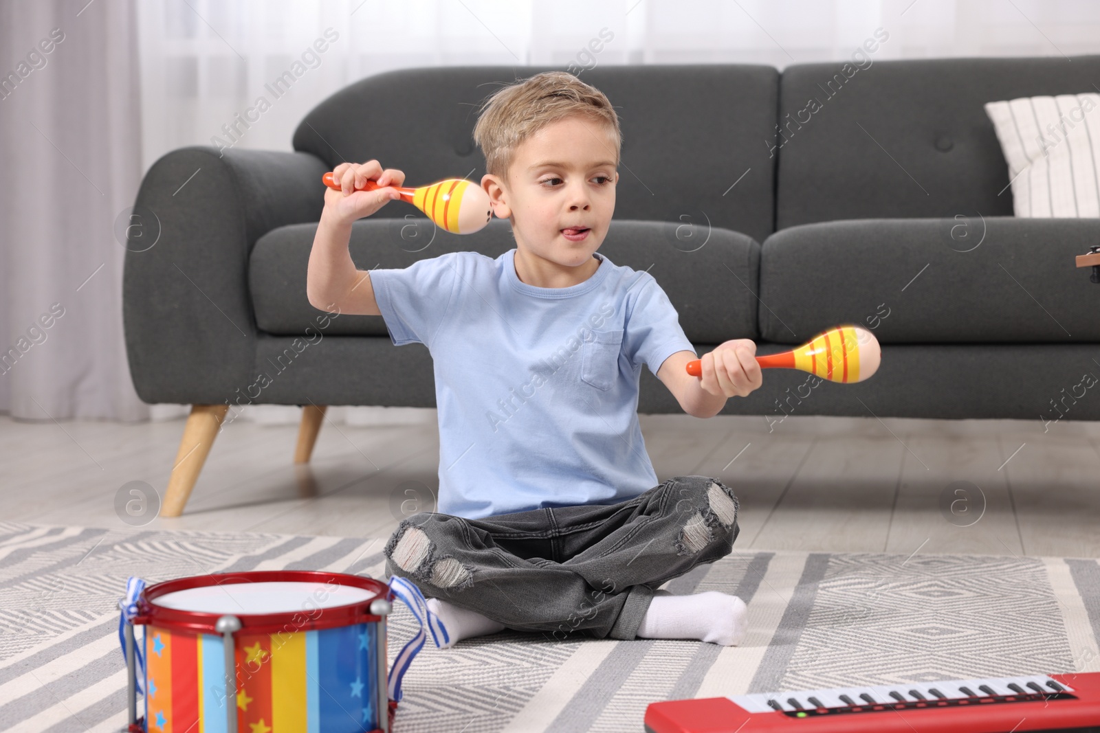 Photo of Little boy playing toy maracas at home