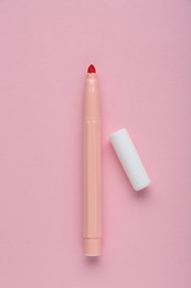 Bright marker and cap on light pink background, flat lay