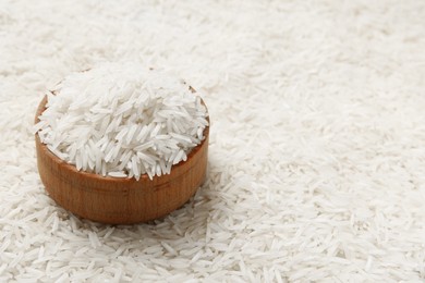 Photo of Bowl on raw basmati rice, closeup. Space for text